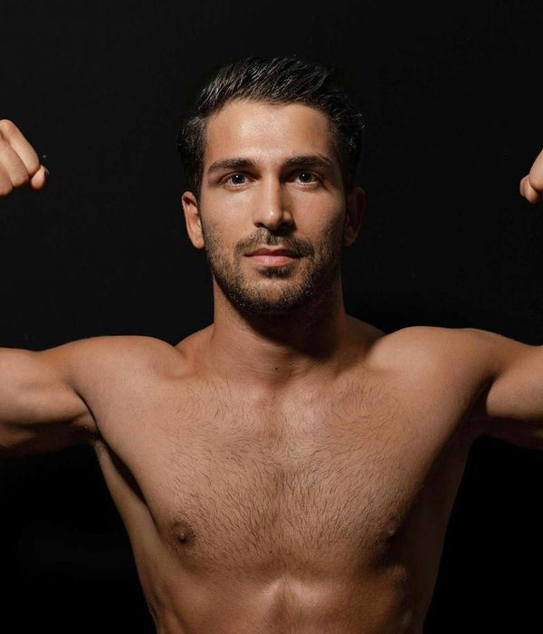 A strong man performing functional strength exercises in a dark studio.